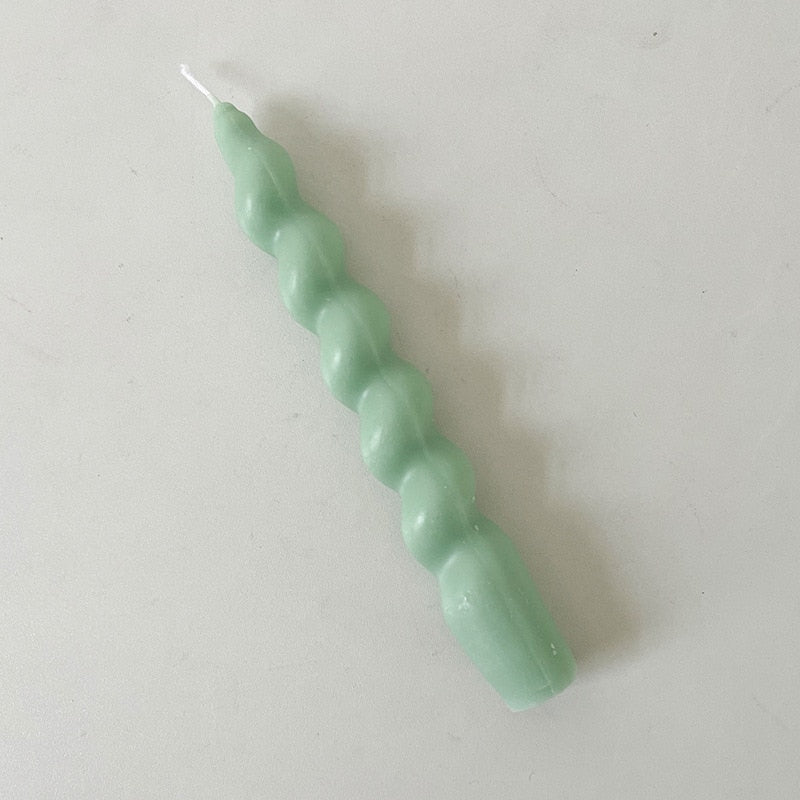 Single twisted tapered candle with a light green colour.